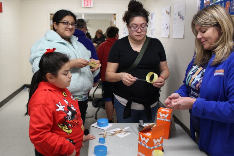 A Cowherd student and her family build catapults out of popsicle sticks, spoons, and rubber bands.