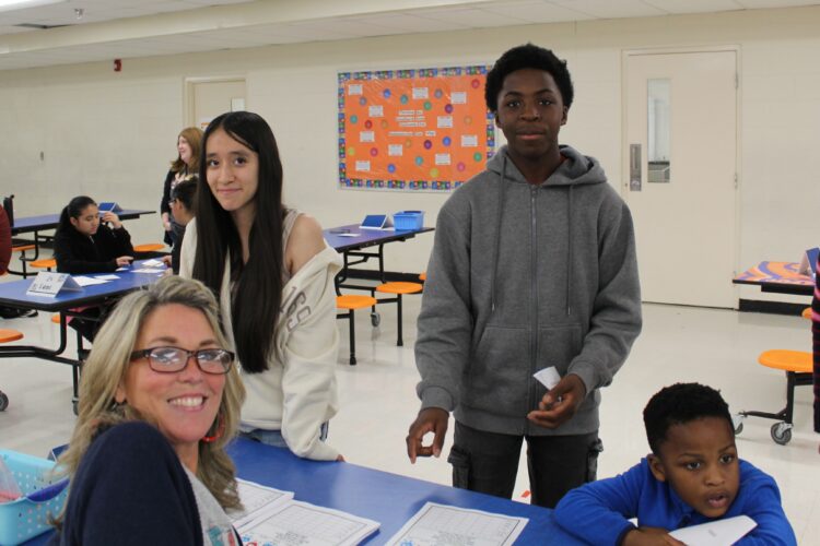 Two students pose with a teacher while playing a math game.