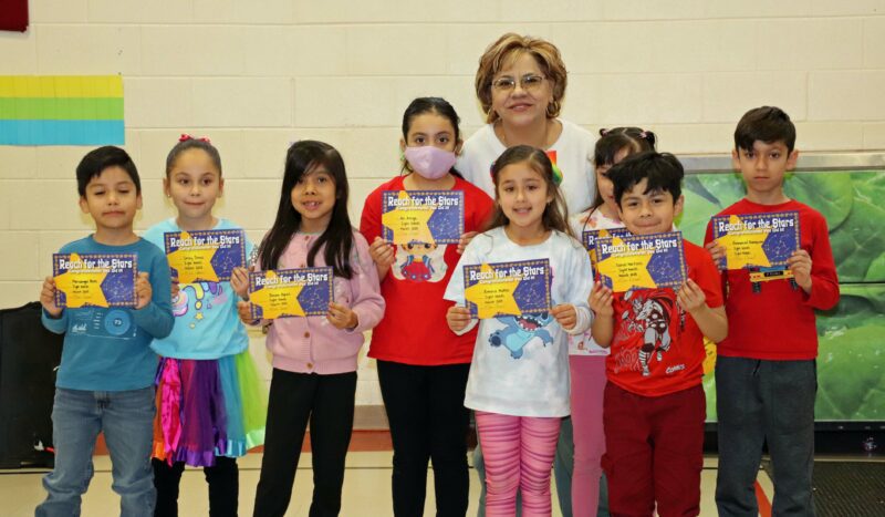 Mrs. Corral smiles with her students receiving awards.