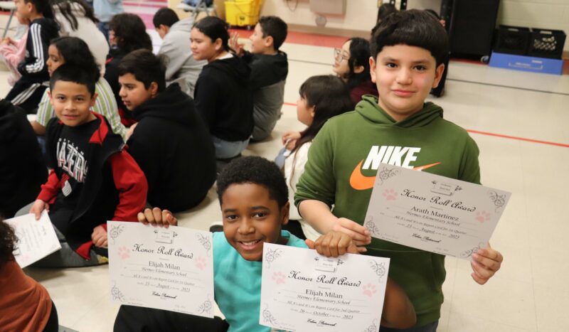 5th graders hold up their awards for honor roll and high honor roll.