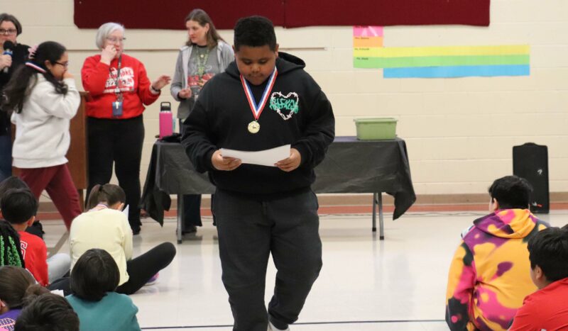 A 5th grader is awarded a medal for his high honor roll achievement.
