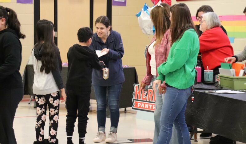 Mrs. Wrigglesworth hands a student an award.